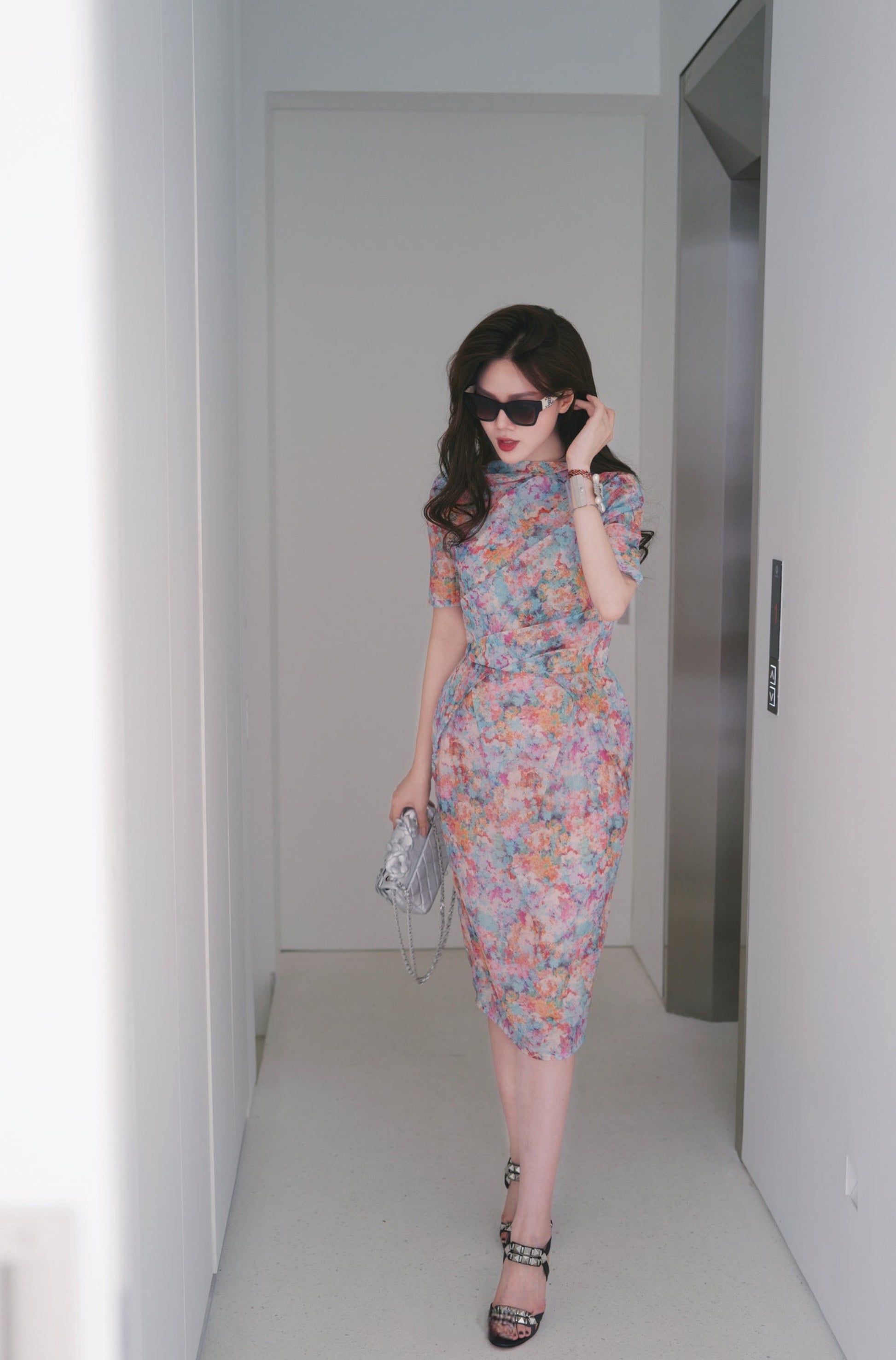 Woman in a floral dress standing in a minimalistic room.